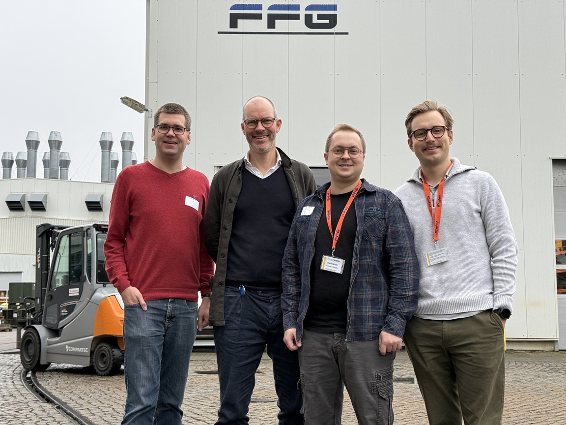 Das Team der Machbarkeitsstudie, vier Männer, posieren nebeneinander vor einer großen Halle, auf das Logo von FFG zu erkennen ist.